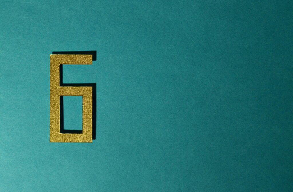 A golden number six on a teal background, perfect for decorative purposes.