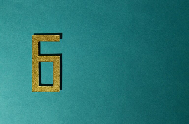 A golden number six on a teal background, perfect for decorative purposes.